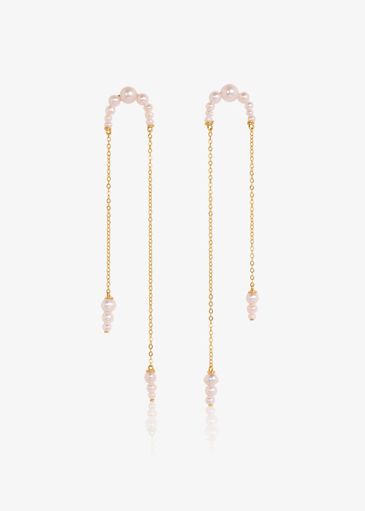Athena - Crafted with descending pearls attached to two asymmetrical chains, these earrings move angelically. The three descending pearls at the bottom of each chain dance in sweet unison, creating a face-framing effect that's captivating and enchanting.