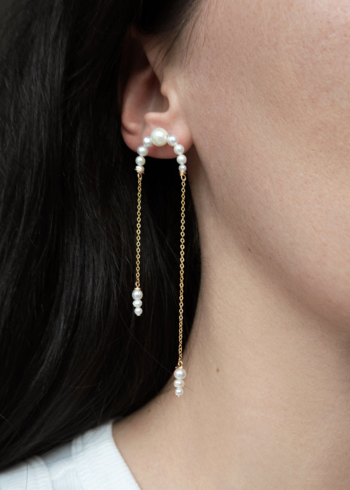14K Athena - Crafted with descending pearls attached to two asymmetrical chains, these earrings move angelically. The three descending pearls at the bottom of each chain dance in sweet unison, creating a face-framing effect that's captivating and enchanti