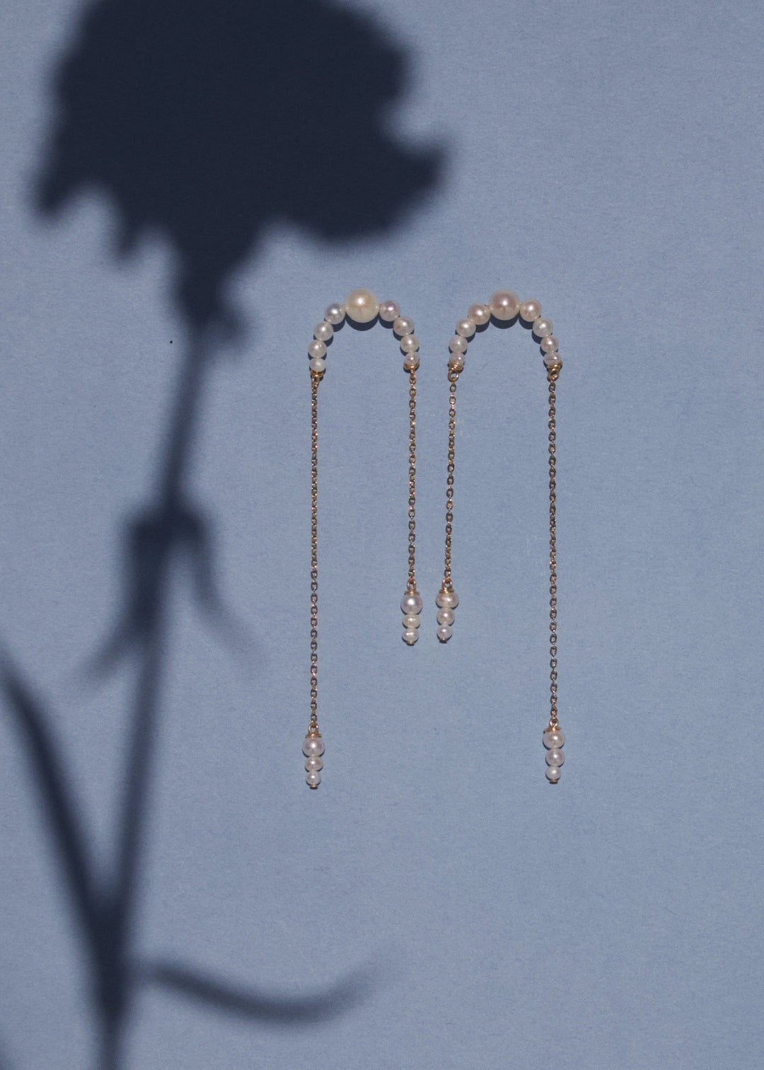 14K Athena - Crafted with descending pearls attached to two asymmetrical chains, these earrings move angelically. The three descending pearls at the bottom of each chain dance in sweet unison, creating a face-framing effect that's captivating and enchanti