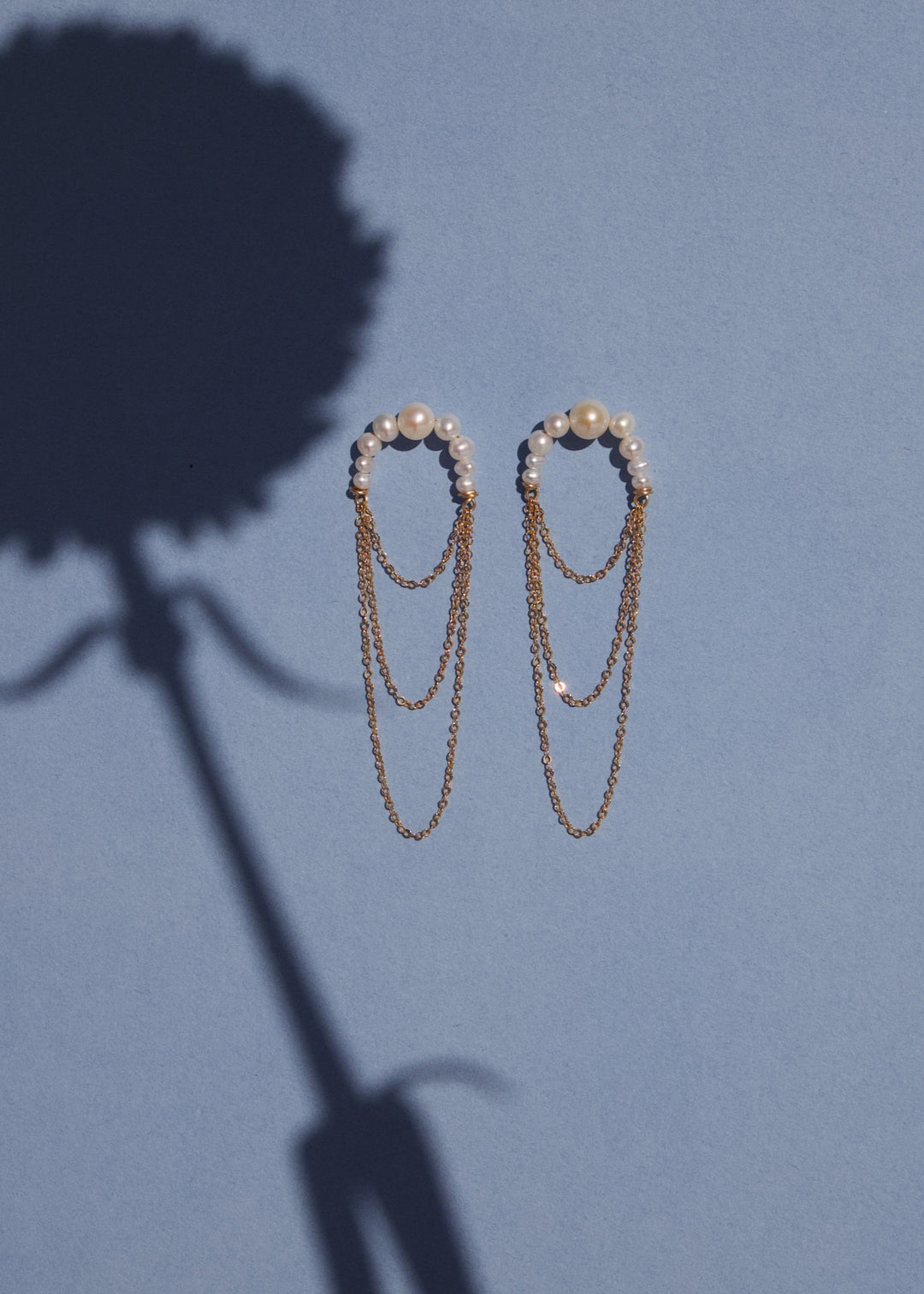 14K Valencia - Crafted with descending pearls elegantly attached to three layers of chain, these earrings create a unique silhouette that maximizes radiance. The lightweight, flowing chains add movement and charm, making them the perfect choice for dancin