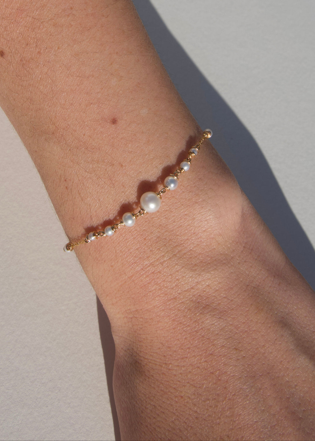Amira Bracelet - A delicate strand of seed pearls tapers from a larger center pearl into a reflective gold chain. Subtle and graceful, the Amira is the perfect dainty piece to layer or wear on its own. 14K Gold-Filled Metals Tarnish-Resistant & Hypoallerg
