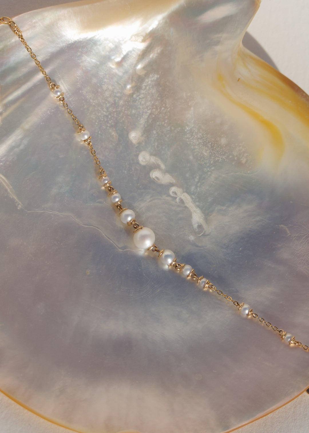 Amira Bracelet - A delicate strand of seed pearls tapers from a larger center pearl into a reflective gold chain. Subtle and graceful, the Amira is the perfect dainty piece to layer or wear on its own. 14K Gold-Filled Metals Tarnish-Resistant & Hypoallerg