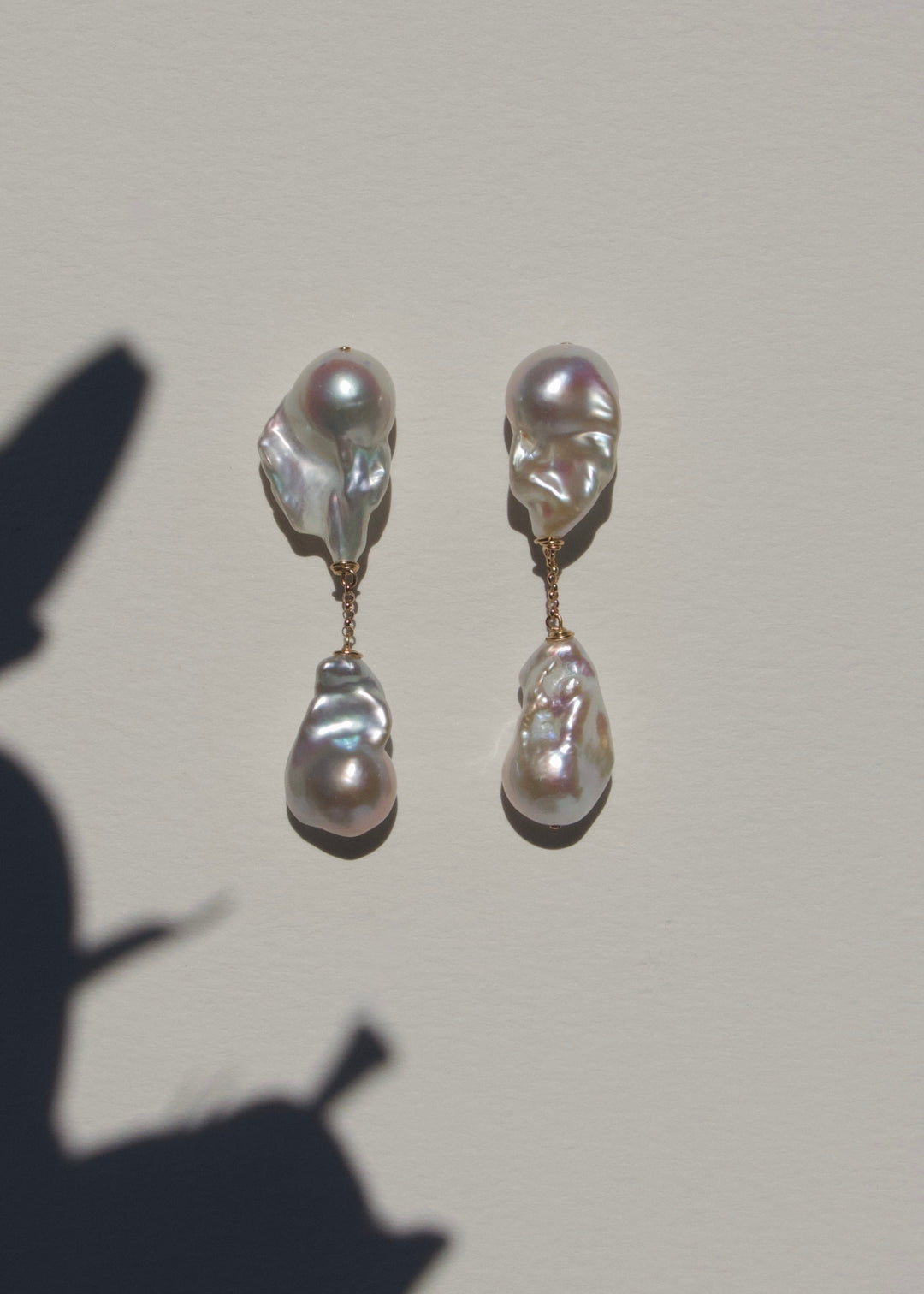 Aria earrings on a light wall with plant shadow