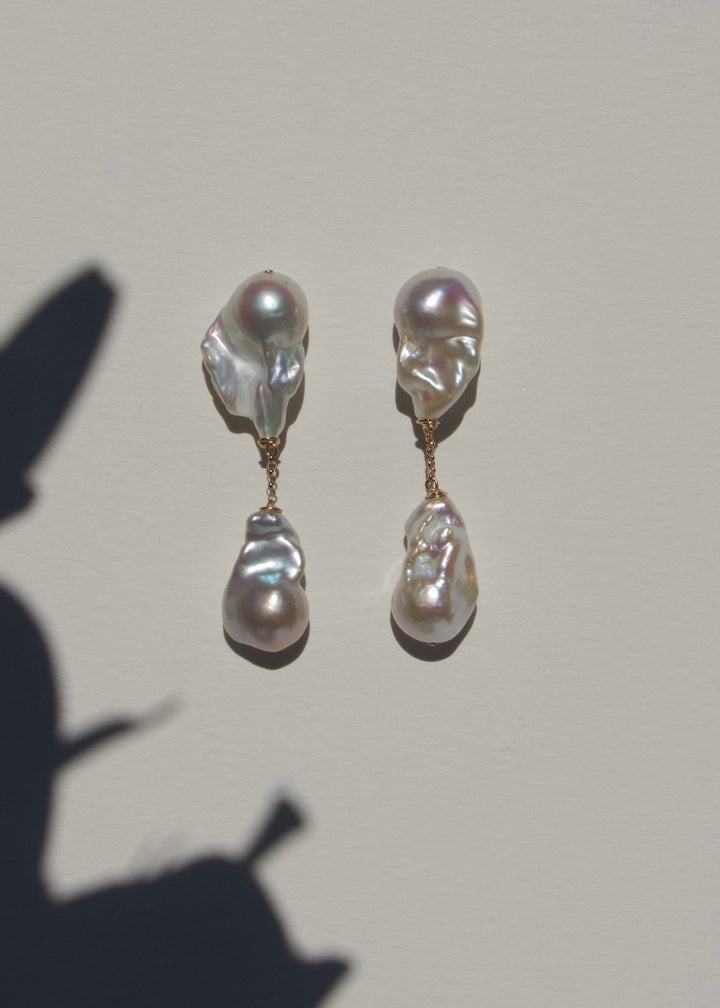 Aria earrings on a light wall with plant shadow