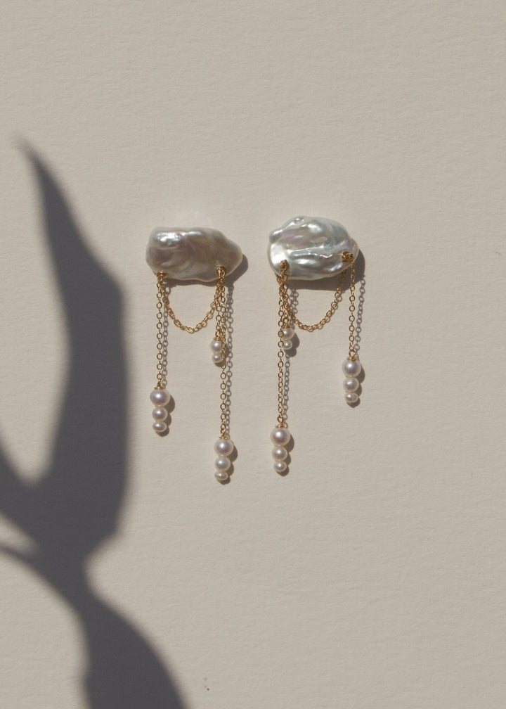 Aurora - These asymmetrical earrings feature cascading seed pearls hanging from cloud like keshi pearls. Suspended from a reflective cable chain, their unique design balances elegance and movement in a strikingly modern way. 14K Solid Gold Freshwater Kesh