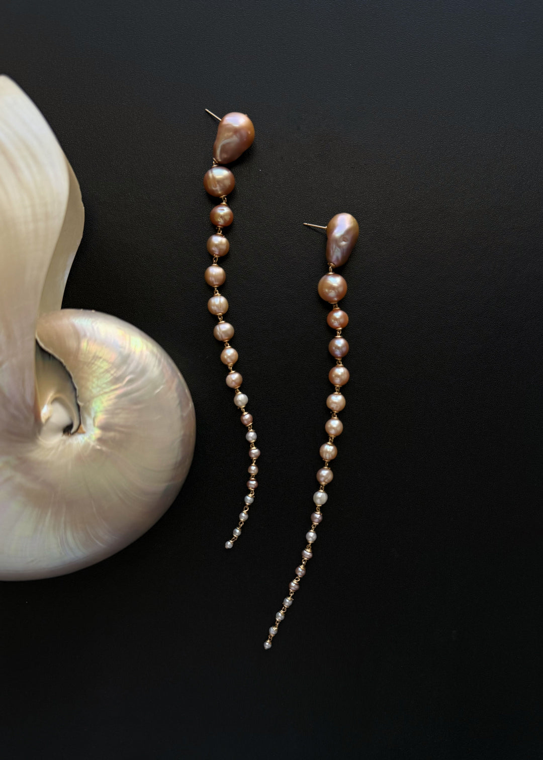 Azalea - Crafted with baroque pink or white pearls that taper into delicate white seed pearls, these earrings are a bold blend of femininity and edge. Striking in every sense, they command attention with their unexpected silhouette. 14K Gold-Filled Tarnis