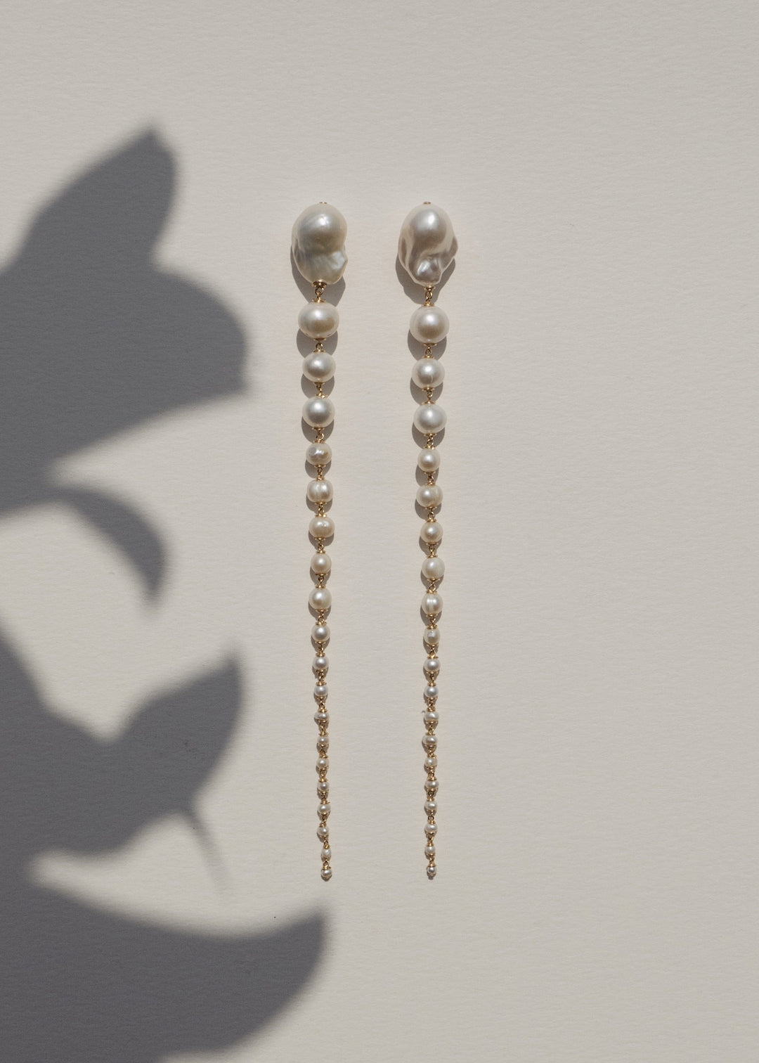 Azalea - Crafted with baroque pink or white pearls that taper into delicate white seed pearls, these earrings are a bold blend of femininity and edge. Striking in every sense, they command attention with their unexpected silhouette. 14K Gold-Filled Tarnis