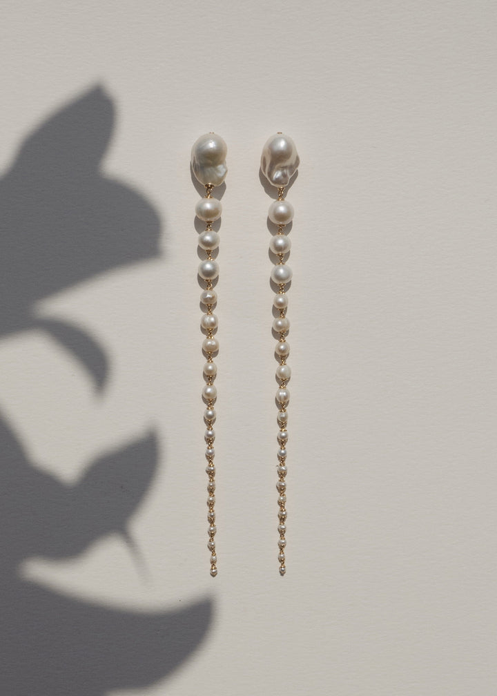 Azalea - Crafted with baroque pink or white pearls that taper into delicate white seed pearls, these earrings are a bold blend of femininity and edge. Striking in every sense, they command attention with their unexpected silhouette. 14K Gold-Filled Tarnis