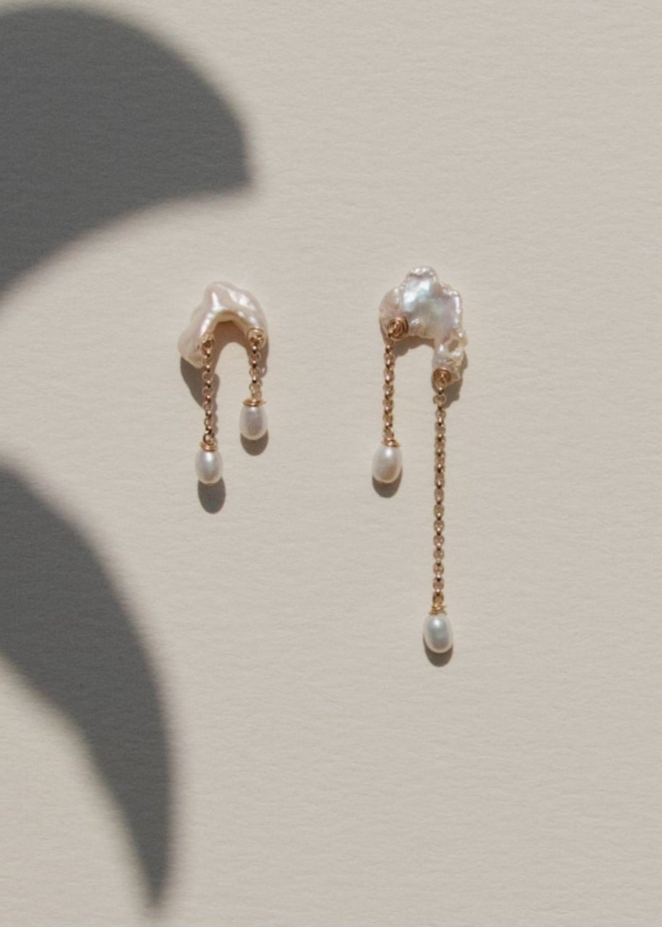 Bridges - Inspired by the natural arches carved into coastal cliffs, these earrings echo the quiet strength of time and tide. Asymmetrical keshi pearls form soft, irregular bridges, each one unique, with subtle curves and texture. From beneath them, rolo