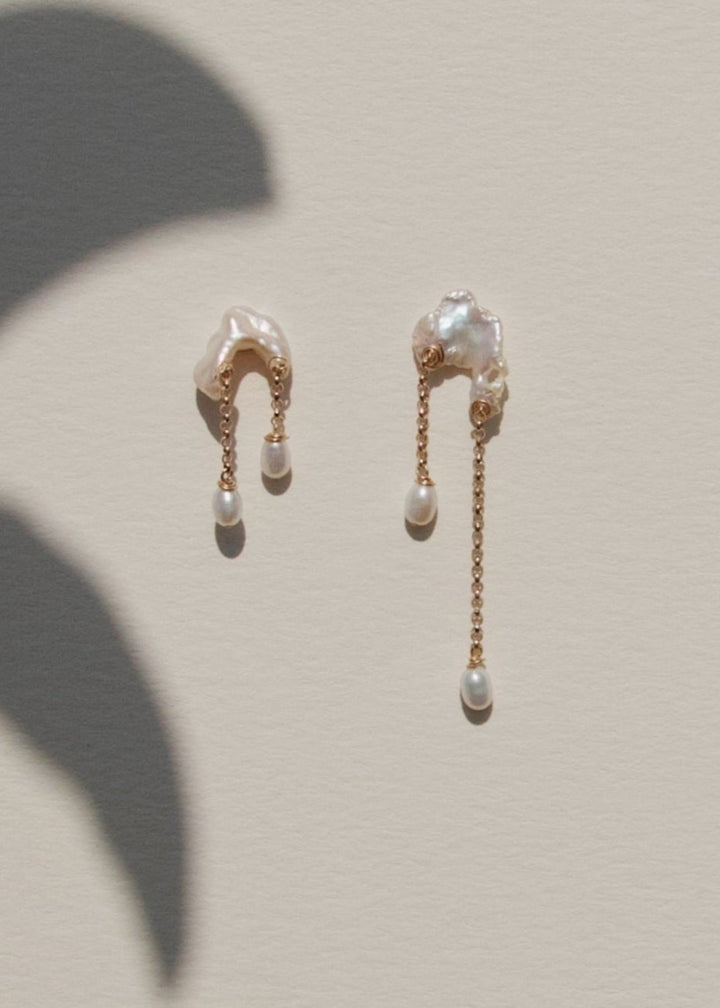 Bridges - Inspired by the natural arches carved into coastal cliffs, these earrings echo the quiet strength of time and tide. Asymmetrical keshi pearls form soft, irregular bridges, each one unique, with subtle curves and texture. From beneath them, rolo