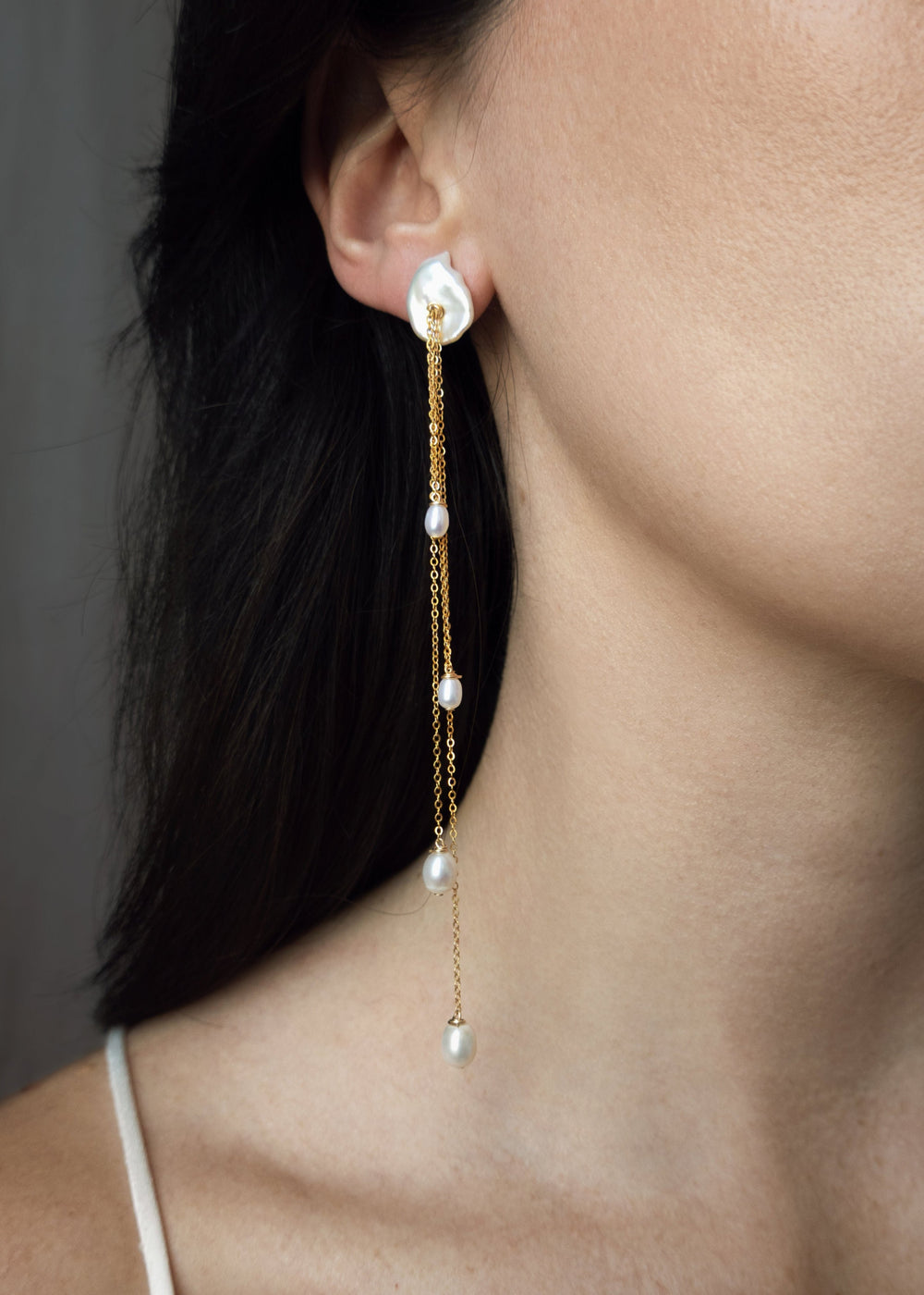 Calla - A more dramatic take on our beloved Lily earrings. Four delicate strands of chain fall at varying lengths, each finished with a glowing teardrop pearl that catches the light with every movement. They’re long, refined, and impossibly dainty. Design