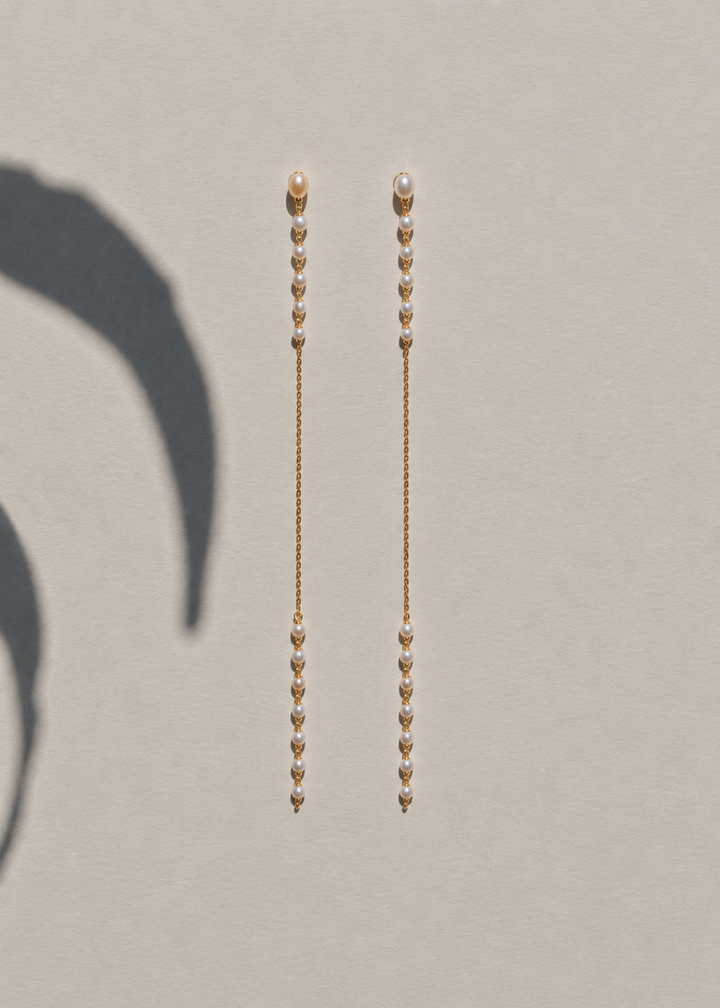 Posy earrings on a beige surface with plant shadow