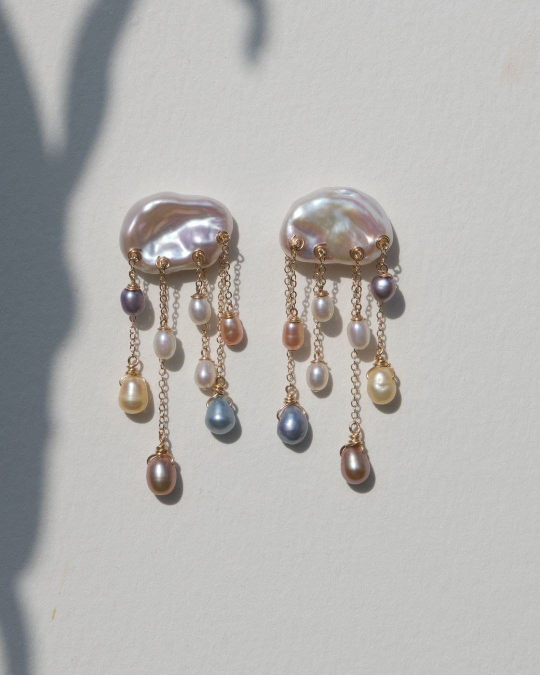 Rainstorm earrings on a beige wall with plant shadow