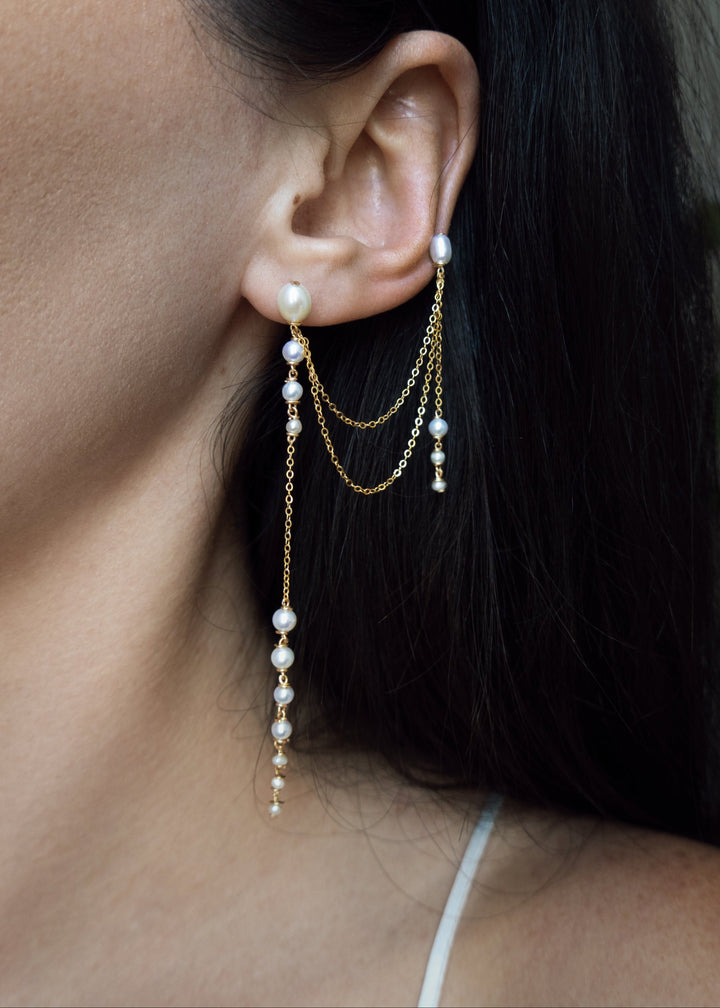 Dahlia - A gentle cascade of seed pearls creates a tapering effect that feels almost weightless. Designed to drape across two piercings the silhouette is delicate, but far from simple. Each pearl moves with quiet intention, catching the light like raindro