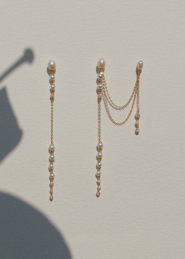 Dahlia - A gentle cascade of seed pearls creates a tapering effect that feels almost weightless. Designed to drape across two piercings the silhouette is delicate, but far from simple. Each pearl moves with quiet intention, catching the light like raindro