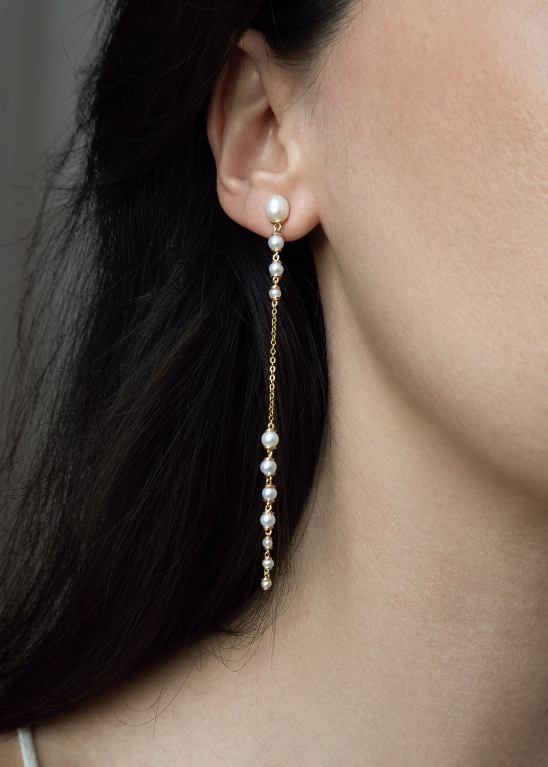 Dahlia - A gentle cascade of seed pearls creates a tapering effect that feels almost weightless. Designed to drape across two piercings the silhouette is delicate, but far from simple. Each pearl moves with quiet intention, catching the light like raindro