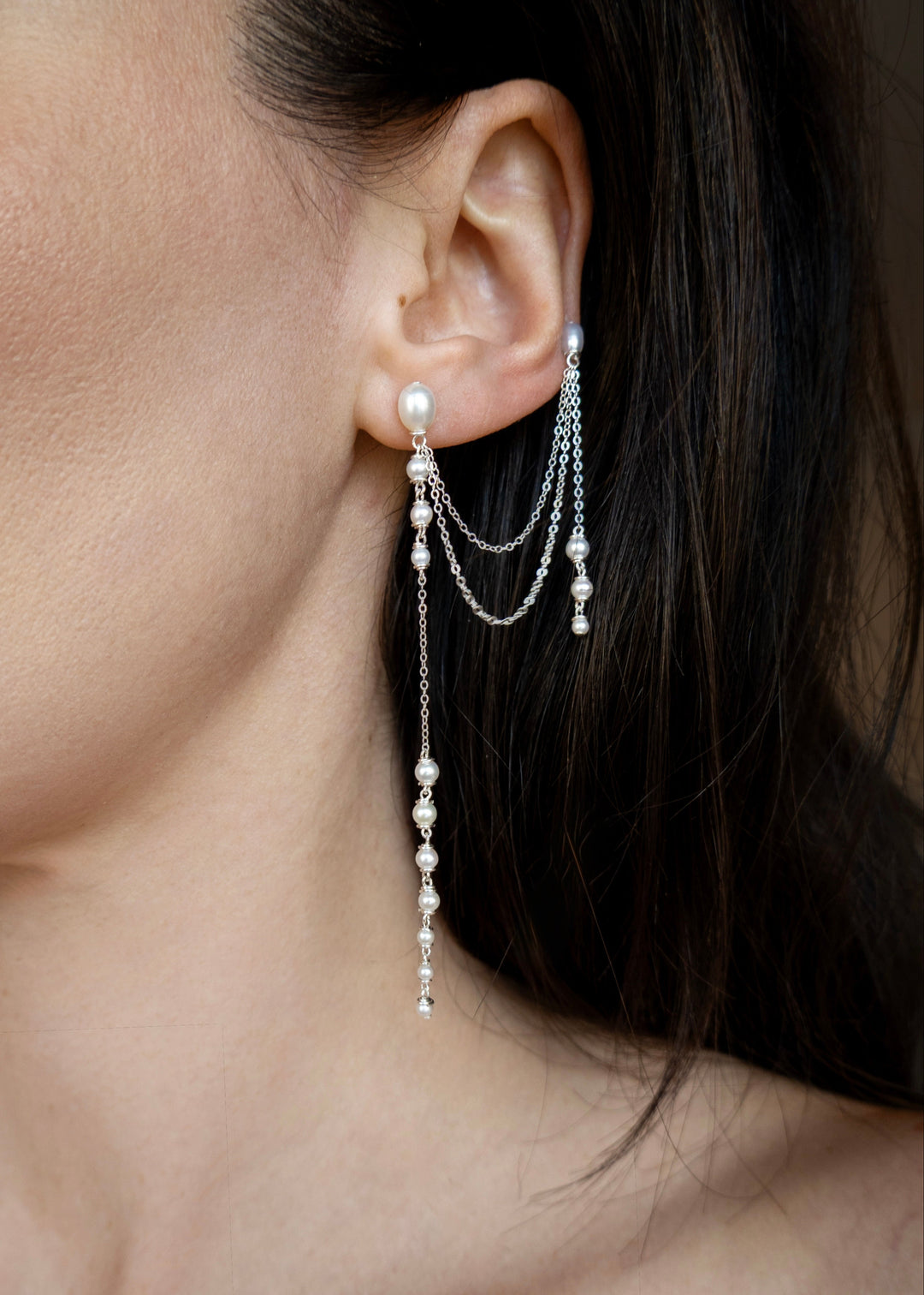 Dahlia - A gentle cascade of seed pearls creates a tapering effect that feels almost weightless. Designed to drape across two piercings the silhouette is delicate, but far from simple. Each pearl moves with quiet intention, catching the light like raindro