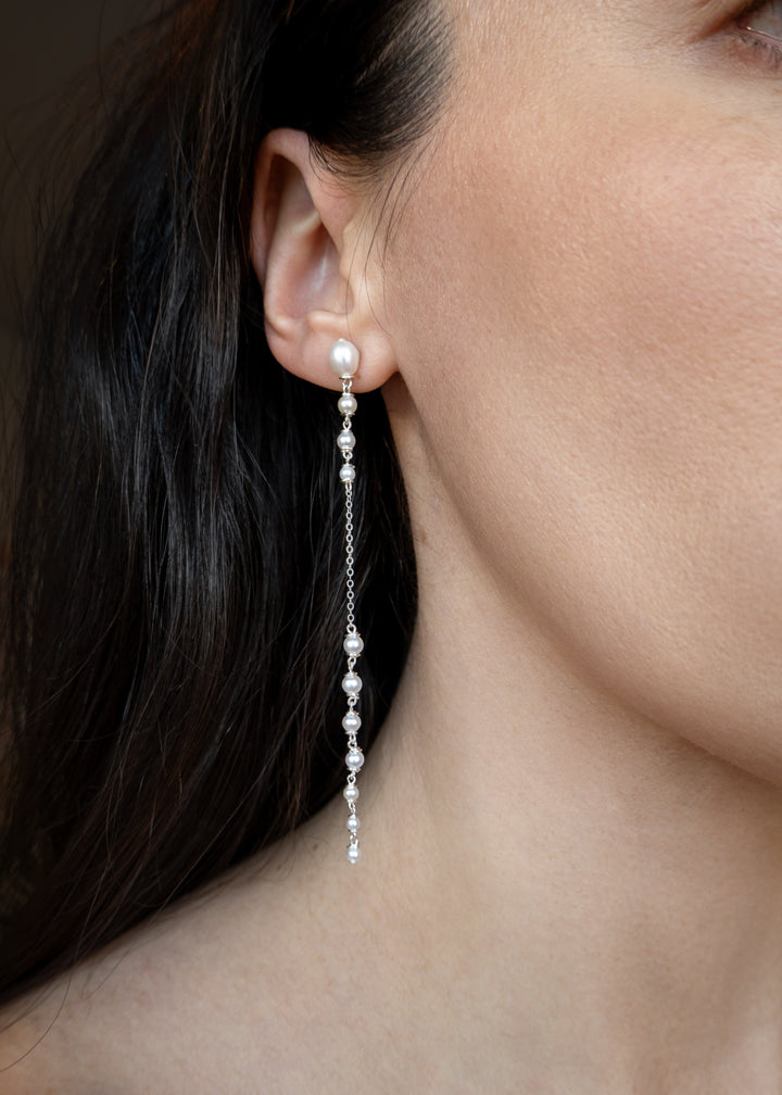 Dahlia - A gentle cascade of seed pearls creates a tapering effect that feels almost weightless. Designed to drape across two piercings the silhouette is delicate, but far from simple. Each pearl moves with quiet intention, catching the light like raindro
