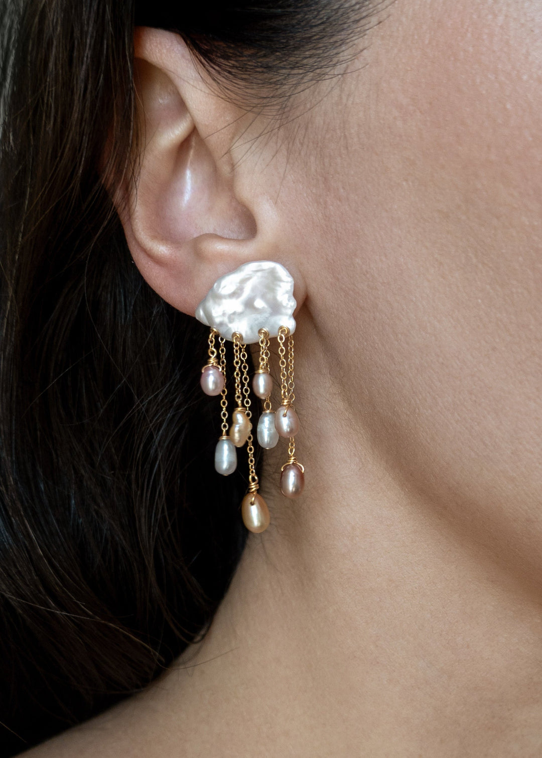 Model wearing a Daydream 14k gold earring with an irregular white keshi pearl top and cascading multicolored teardrop pearls.