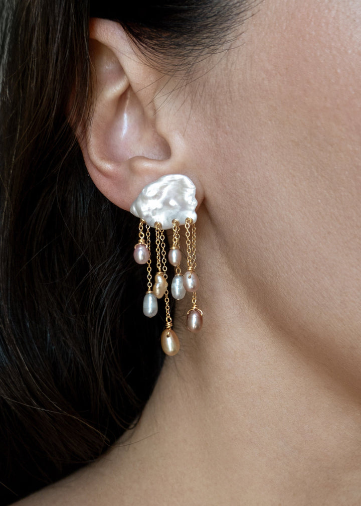Model wearing a Daydream 14k gold earring with an irregular white keshi pearl top and cascading multicolored teardrop pearls.