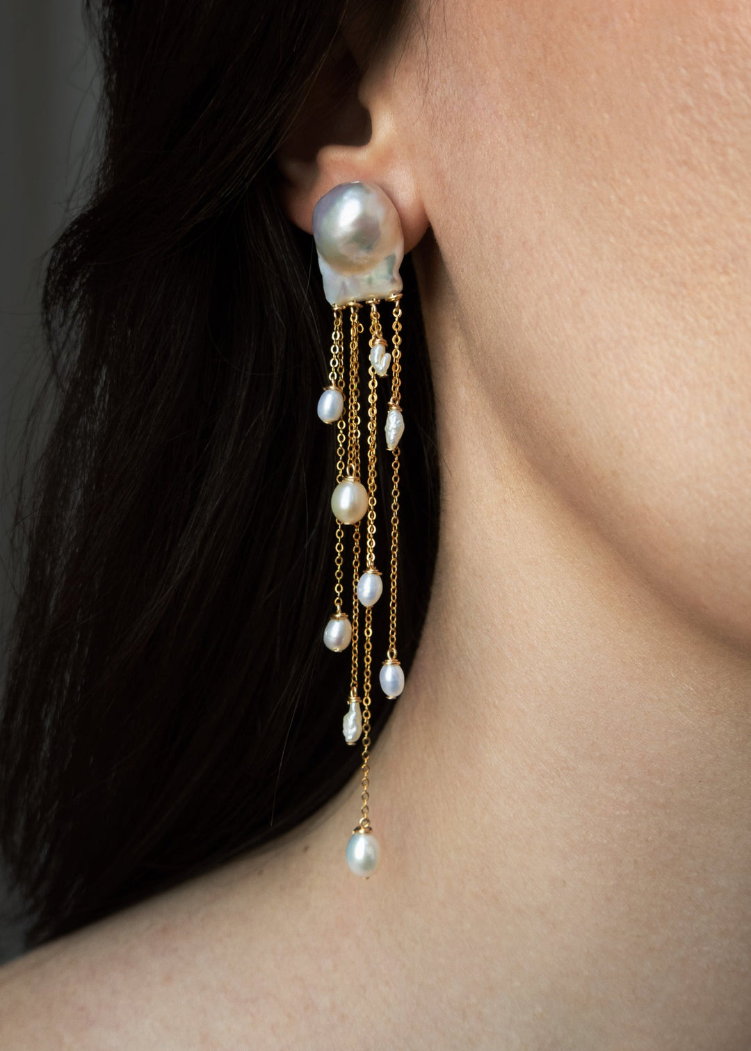 Gia - Like something drifting just beneath the surface, delicate, fluid, and quietly striking. Two baroque pearls anchor cascading chains of varied lengths, each adorned with luminous pearls in unexpected shapes. At four inches long, they move with ease a