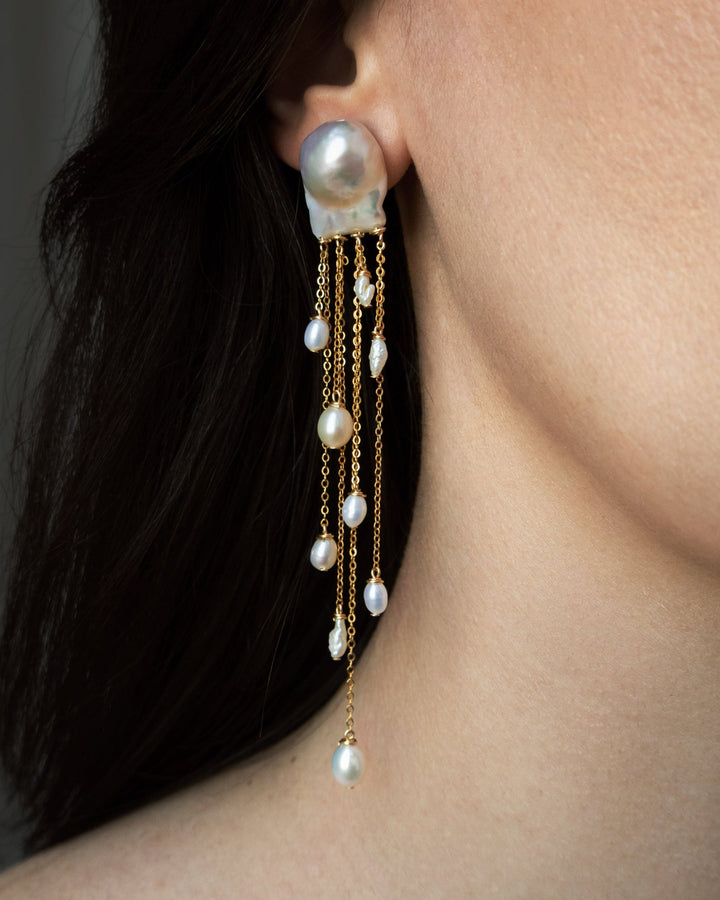 Gia - Like something drifting just beneath the surface, delicate, fluid, and quietly striking. Two baroque pearls anchor cascading chains of varied lengths, each adorned with luminous pearls in unexpected shapes. At four inches long, they move with ease a