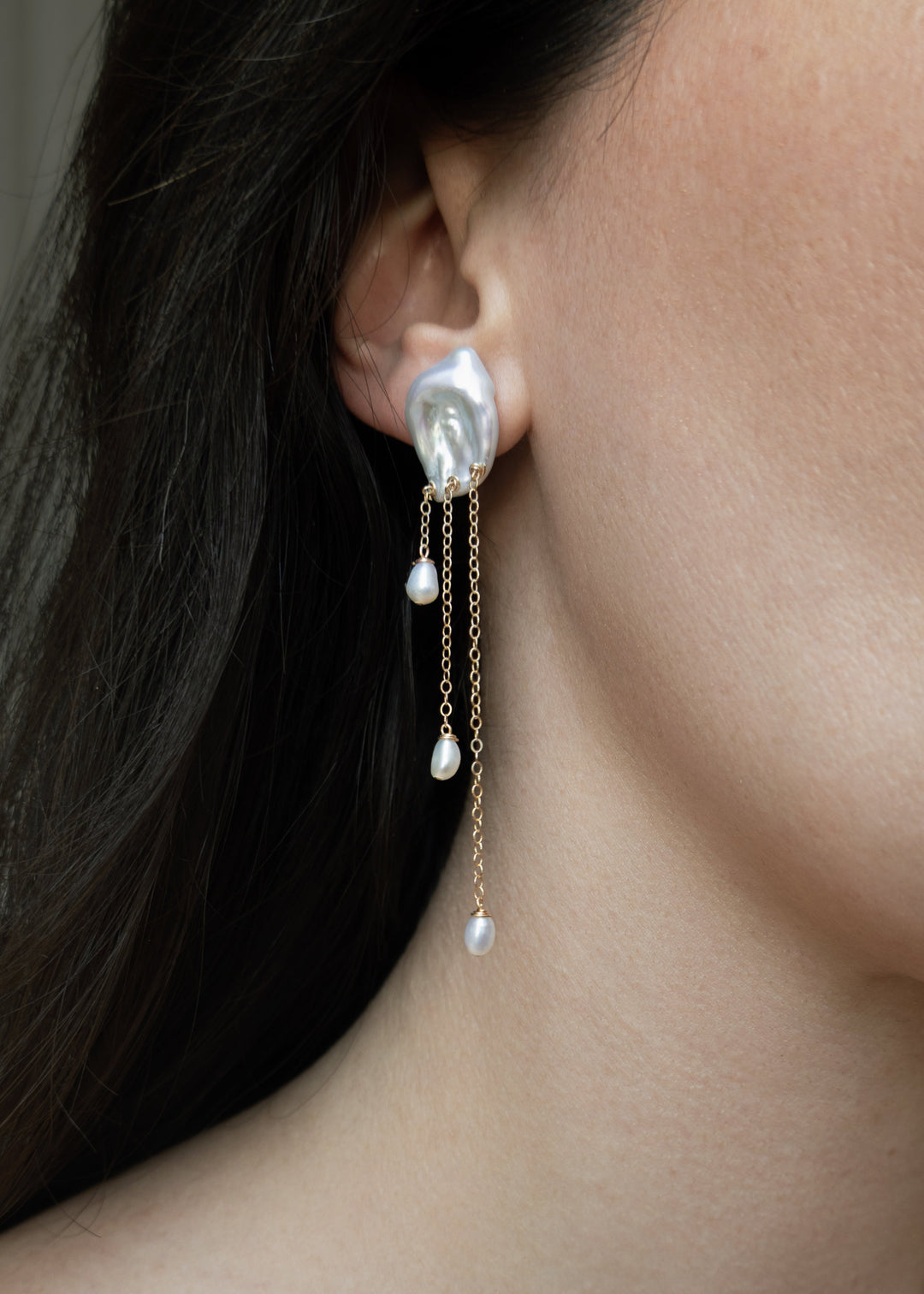 Laguna - These keshi pearls ripple like water touched by a falling drop soft, fluid, and full of light. Suspended below, three 14k gold chains fall at varying lengths, cascading like a quiet stream. Reflective and refined, they bring a sense of calm movem