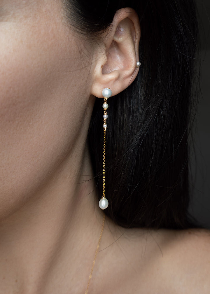 Lucine Earrings - Three inches of effortless elegance. These earrings feature pearls that flow from larger to smaller, ending in a single teardrop pearl. Suspended from a reflective chain, the Lucine Earrings pair beautifully with the Lucine Necklace for