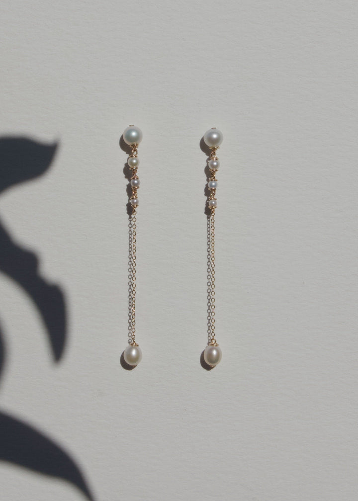 Lucine Earrings - Three inches of effortless elegance. These earrings feature pearls that flow from larger to smaller, ending in a single teardrop pearl. Suspended from a reflective chain, the Lucine Earrings pair beautifully with the Lucine Necklace for