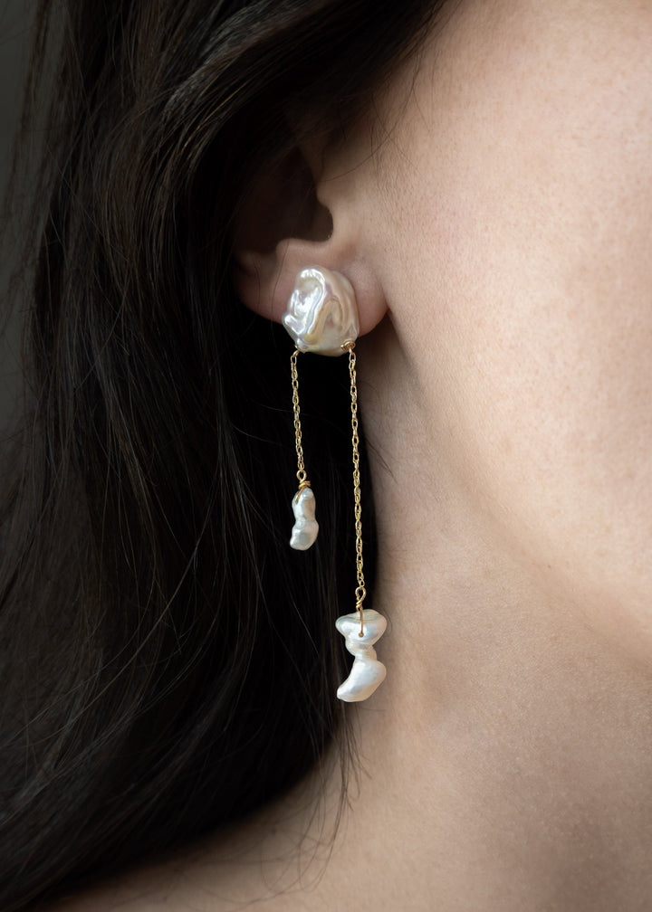 Close-up of a woman wearing pearl earrings with a dark background