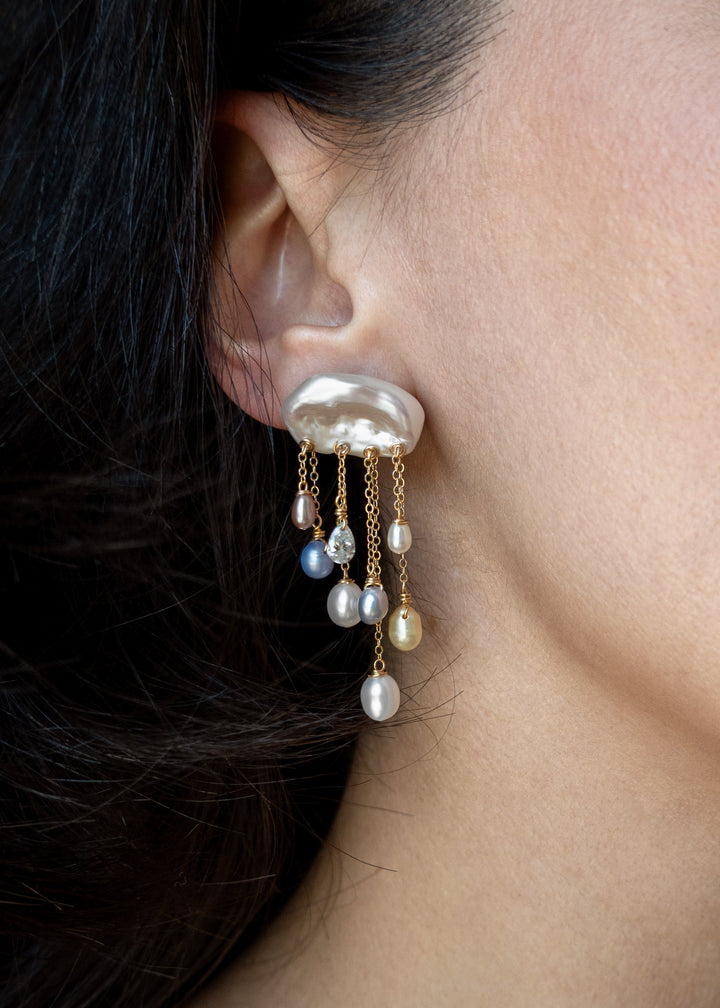 Model wearing a Moonlight 14k gold earring with an irregular white keshi pearl top and cascading teardrop pearls and diamonds.