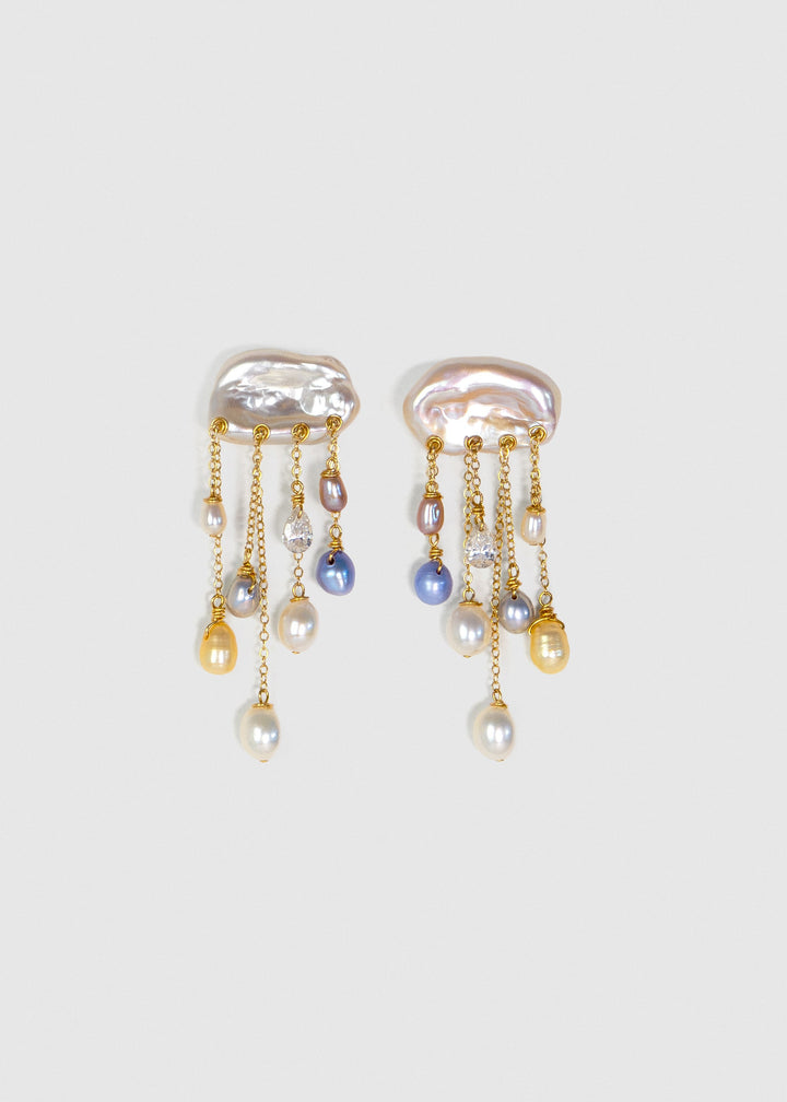 Moonlight 14k gold earrings with white keshi pearl tops, colorful teardrop pearls and diamonds suspended from fine chains on a light background.