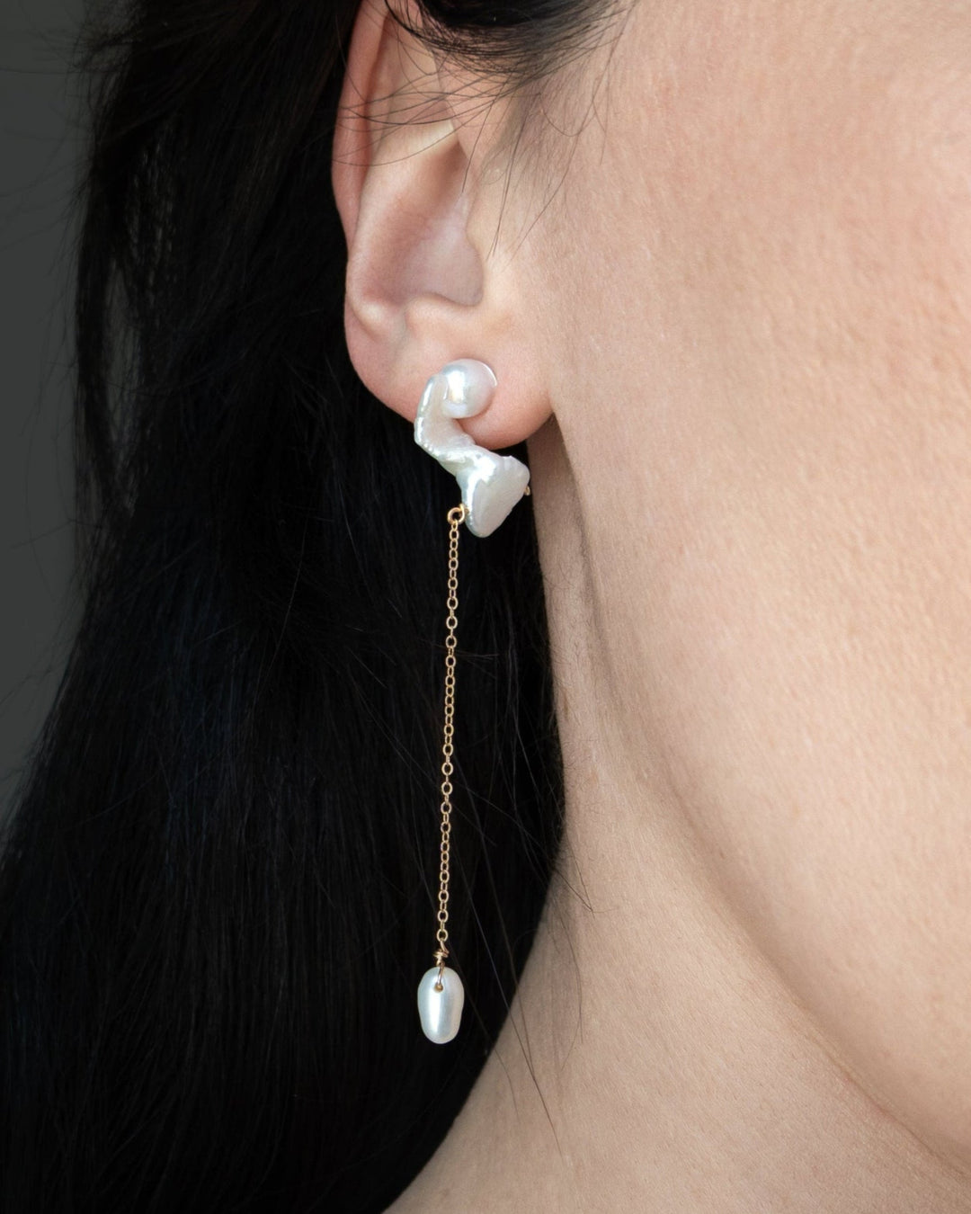 Nova - These asymmetrical earrings feature a crescent-shaped pearl on one side, evoking the delicate curve of the moon. Dainty chains hang from each end, with a teardrop pearl dangling at the bottom, creating an elegant design that balances softness and c
