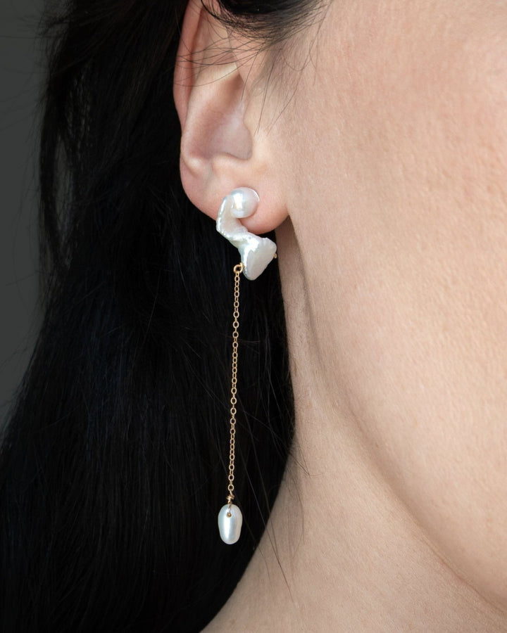 Nova - These asymmetrical earrings feature a crescent-shaped pearl on one side, evoking the delicate curve of the moon. Dainty chains hang from each end, with a teardrop pearl dangling at the bottom, creating an elegant design that balances softness and c