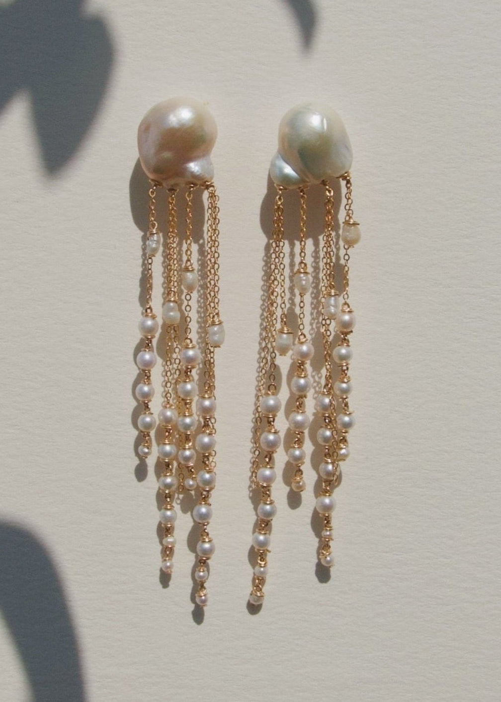 Opal - There’s a rhythm to these earrings. Fluid and mesmerizing, like the pull of the ocean. Eight strands of seed pearls taper gently downward, floating alongside draped gold chains that shimmer with every step. At nearly four inches long, they’re bold
