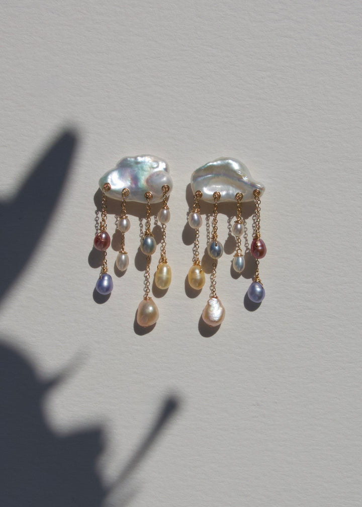 Rainstorm earrings on a light wall with plant shadow