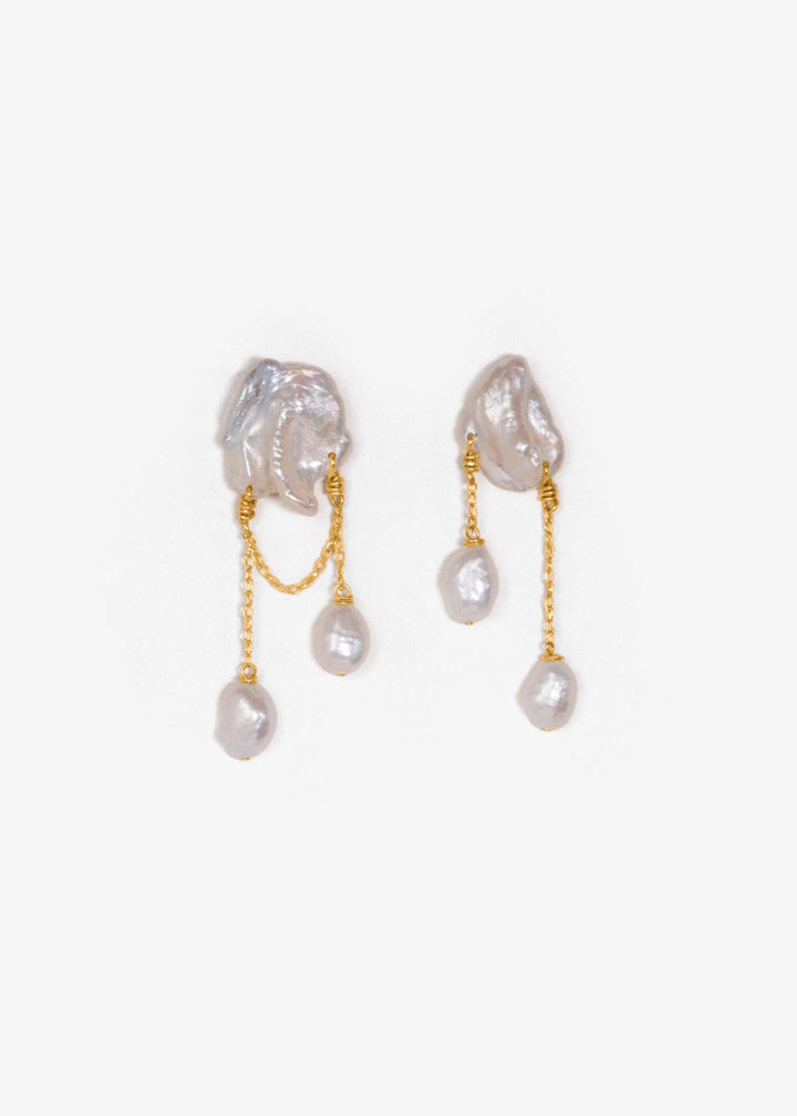 Rhea - These earrings feature two white keshi pearls, their asymmetrical design creating a striking yet playful balance of edge and elegance. Suspended from a substantial chain, pink baroque pearls dangle below, adding a sweet touch to the bold, modern si
