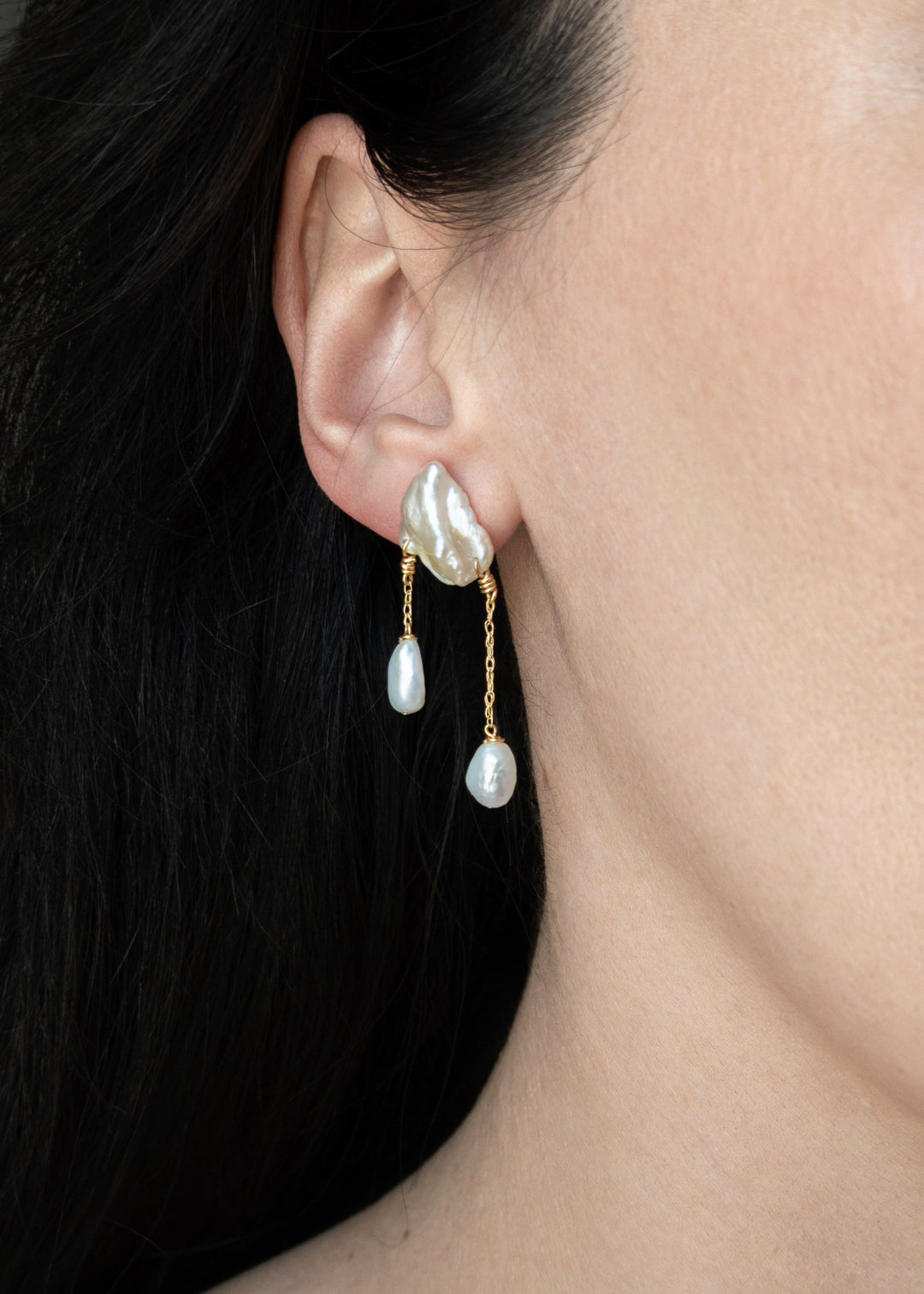 Rhea - These earrings feature two white keshi pearls, their asymmetrical design creating a striking yet playful balance of edge and elegance. Suspended from a substantial chain, pink baroque pearls dangle below, adding a sweet touch to the bold, modern si