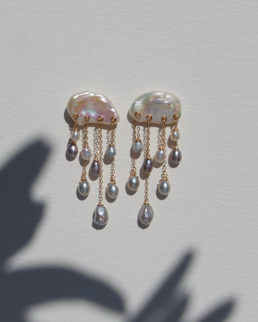 Dewdrop earrings on a light wall with plant shadow