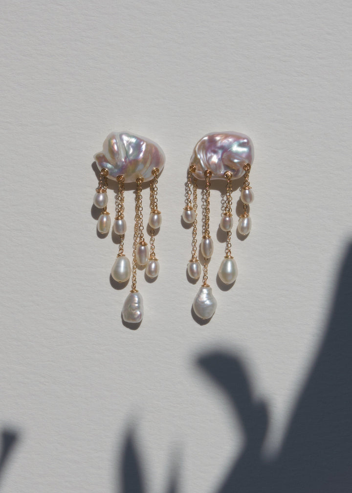 Snowfall earrings on a light wall with plant shadow