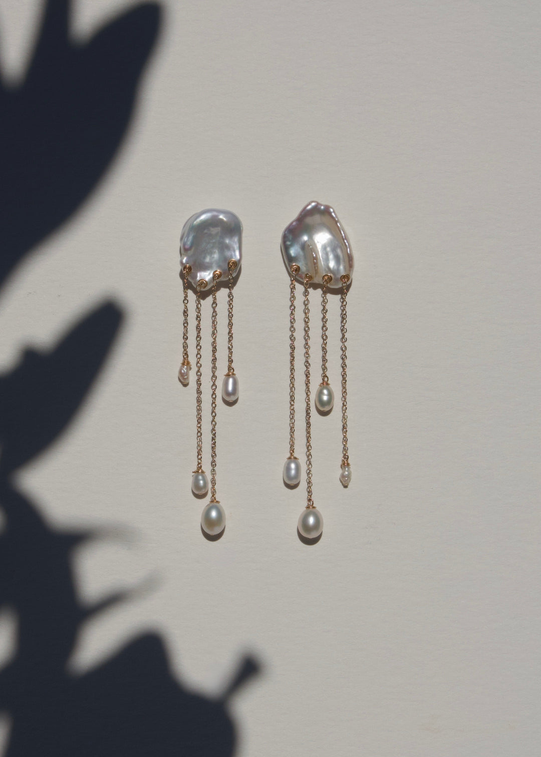 Sierra earrings on a light wall with plant shadow