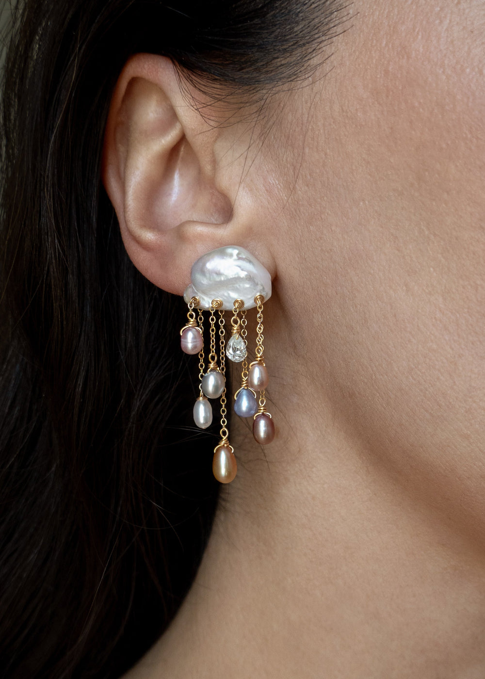 Model wearing a Stardust 14k gold earring with a white keshi pearl top and cascading multicolored pearls and diamonds.