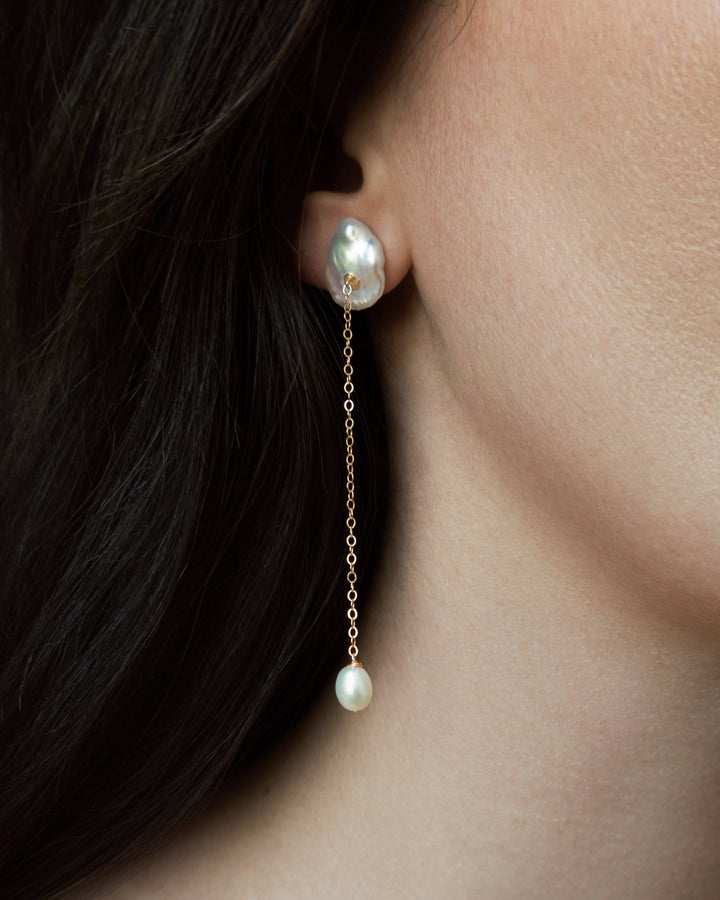 Viv - These earrings feature a single medium sized keshi pearl with a delicate 14k gold chain that falls gracefully below. At the end, a soft teardrop pearl adds a subtle glow and movement. Perfect for those who love something minimal yet distinct, especi