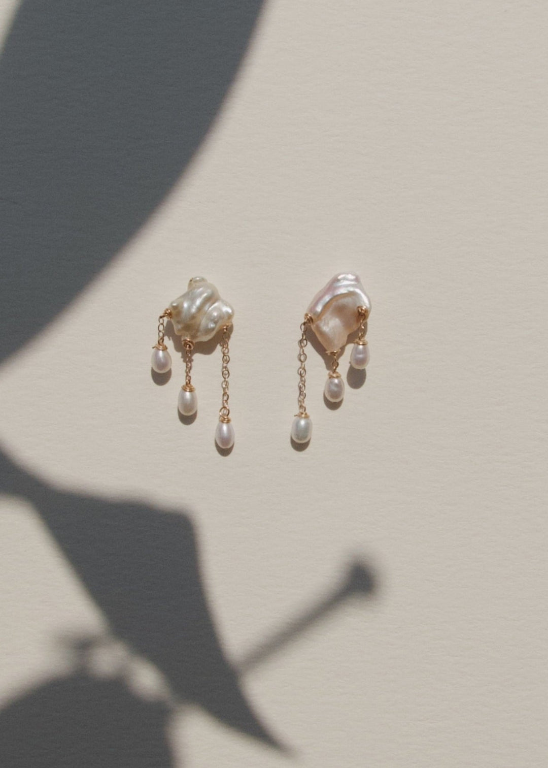 Pair of gold earrings with pearl-like stones on a beige background