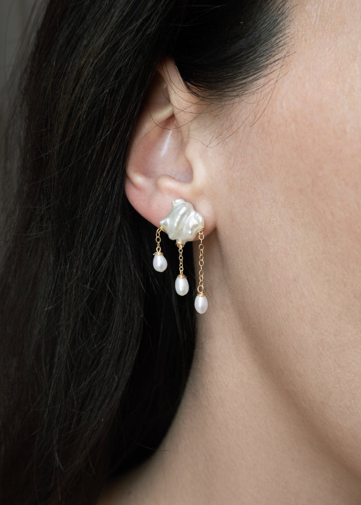 Close-up of a woman wearing pearl earrings with a neutral background